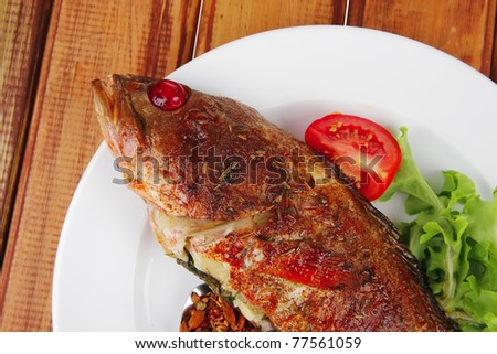 savory on plate : roast golden fish served on fish plate with lemon tomatoes and spices