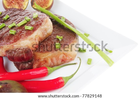 main entree : roasted beef lamb steak served with hot cayenne peppers green chives and sweet figs on plate isolated over white background