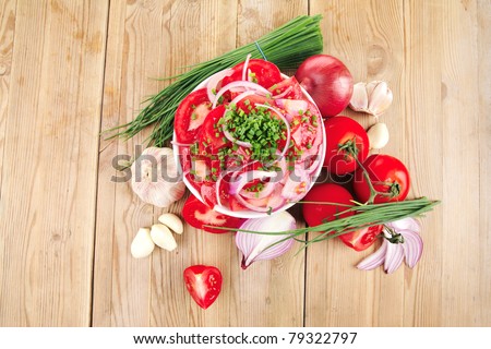 vegetable food : fresh tomato salad in white bowl with bundle of chives and raw tomatoes on twig over wooden table