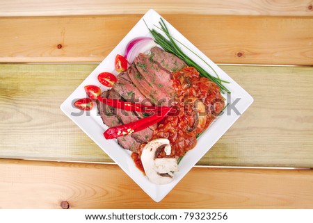 beef slice on white plate with peppers wooden table