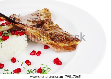 meat savory: roast veal ribs with rice garnish and pomegranate seeds over white background