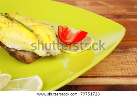 grilled fish fillet served over wood with tomatoes,olives and bread