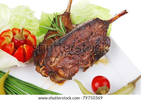 savory plate: grilled ribs on white plate with chives, red hot peppers lettuce isolated white background