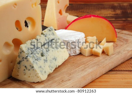 image of cheeses on wooden plate over table