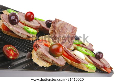 snakes on grill plate : small sandwiches with sliced meat and supplements isolated over white background
