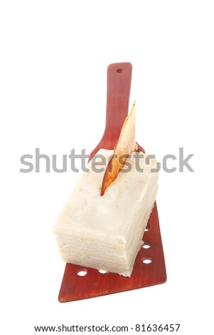 small cream cake on wooden spatula over white