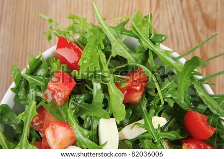 healthy food : salad with raw tomato , garlic , and green staff in white bowl over wood served with cutlery