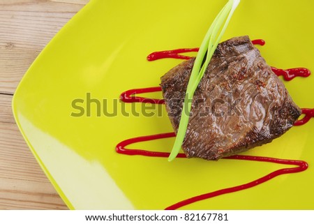 meat food : roast beef fillet mignon served on green plate with chives and ketchup over wooden table