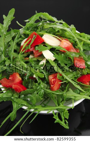healthy appetizer : salad with raw tomato , garlic , and green staff in white bowl on black background