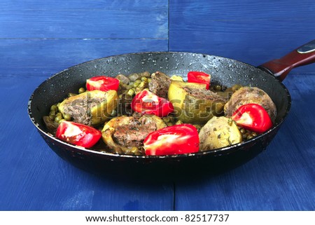 homemade cuisine: zucchini filled meat with peas, beans and tomatoes on black used pan