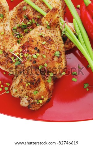 savory food : roasted chicken legs garnished with green sprouts and peppers on red plate isolated over white background