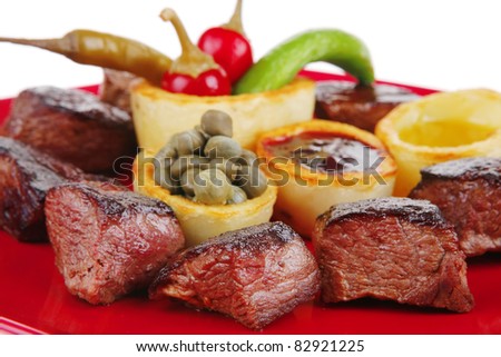 european food: roast beef meat over red plate isolated on white background with hot peppers, capers , olives oil , and bbq sauce