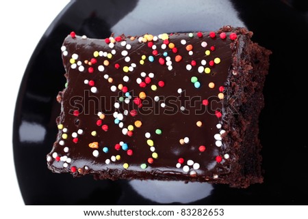 dessert : chocolate cake coated with chocolate on black saucer isolated over white background
