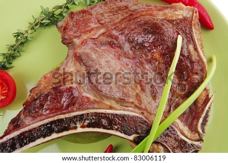 meat food : roast rib on green dish with thyme pepper and tomato isolated over white background