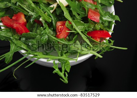 healthy food : salad with raw tomato , garlic , and green staff in white bowl on black background