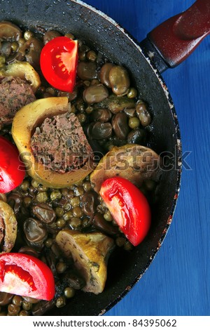homemade cuisine: zucchini filled meat cooked with peas and tomatoes on black pan