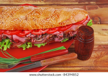 french sandwich : fresh white baguette with chicken smoked sausage over red plate on wood