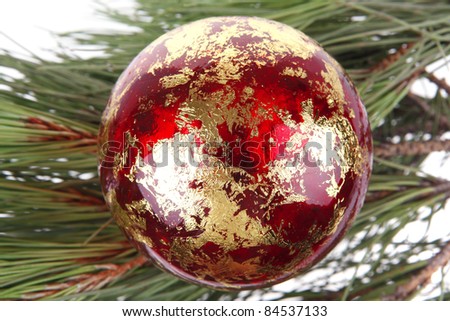 metallic christmas holiday toys with shiny red garland on fir tree twig isolated over white background