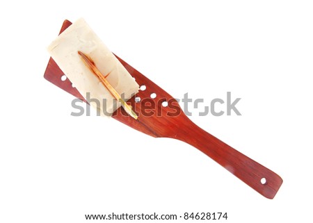 small cream cake on wooden spatula over white
