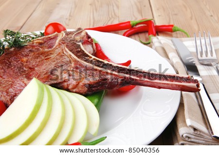 meat food : grilled beef spare rib on white dish with thyme pepper and tomato on wooden table