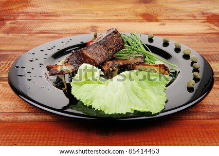 served meat: spiced barbecued ribs on black plate with vegetables