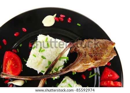 meat food: ribs on black with rice garnish and tomatoes on black over white background