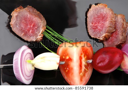 meat food : grilled fat meat served on black plate with vegetables on spit isolated on white background