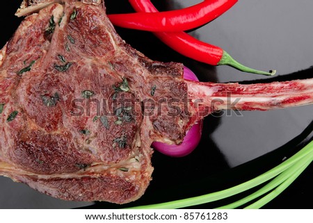 served main course: boned roasted lamb ribs served with green chives and red chili peppers on black board