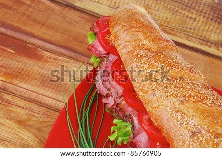 french sandwich : fresh white baguette with chicken smoked sausage over red plate on wood