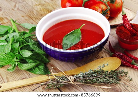 diet food : fresh cold tomato soup with basil thyme and dry pepper in big bowl on wood table