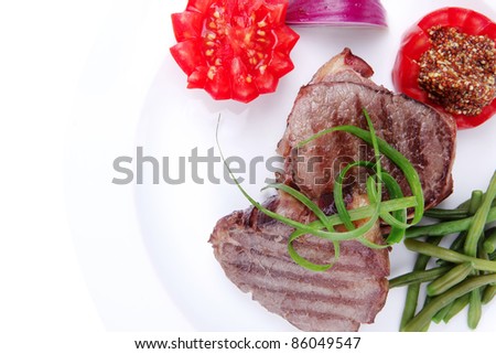 roasted beef meat strips steak on white ceramic plate with sweet pea and tomatoes isolated over white background