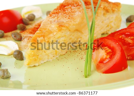 food : vegetable casserole triangle on green plate with cheese and tomatoes isolated on white