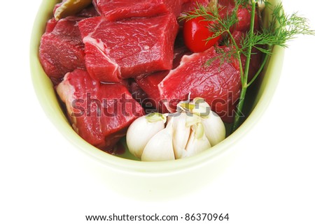 raw fresh beef meat slices in a ceramic dish with onion and red peppers isolated over white background