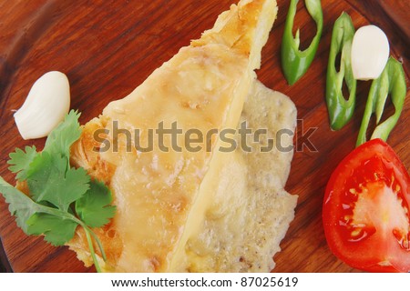 dairy food : cheese casserole piece on wooden plate tomatoes , chives , and garlic isolated over white background