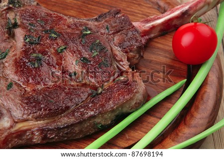 served main course: boned roasted lamb ribs served with green chives and cherry tomato on wooden plate