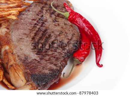 entree : grill beef meat steak on white round plate with dry hot chili pepper and potato chips isolated on white background