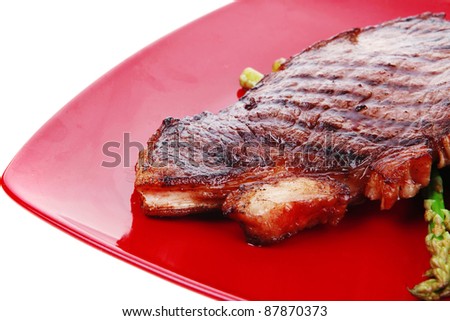 meat table : grilled beef fillet with asparagus served on red dish isolated over white