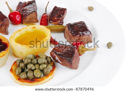 european food: grilled meat goulash on white plate with hot pepper, capers and sauces