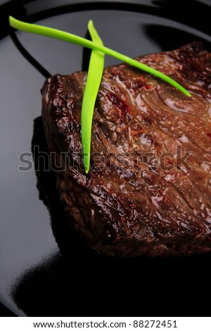 meat food : roasted fillet mignon on black plate with chili pepper and chives isolated over white background