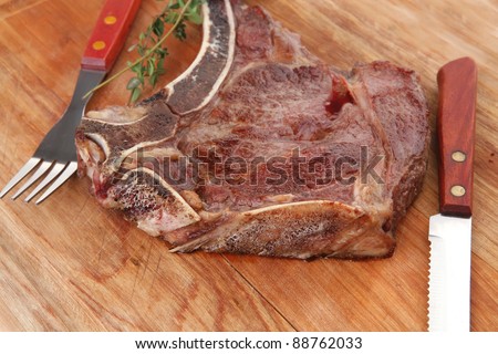 savory : roasted beef spare rib on wooden plate with cutlery and thyme i