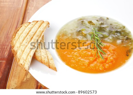 european cuisine: dual components vegetable soup served with toasts on wood