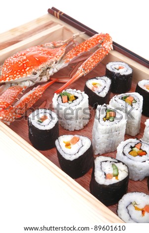Maki Rolls and California rolls made of fresh raw Salmon, Tuna and Eel with Cream Cheese and Avocado . Isolated over white background . on wooden plate with live crab . Maki Sushi and Nigiri