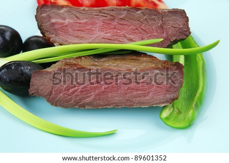 meat food : roast beef fillet mignon served on blue plate with chili pepper and tomatoes over blue wooden table