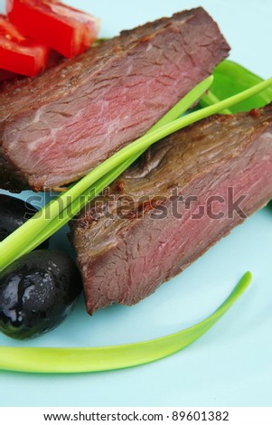 meat food : roast beef fillet mignon served on blue plate with chili pepper and tomatoes over blue wooden table