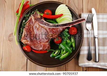meat food : grilled beef spare rib on dark dish with thyme pepper and tomato on wooden table