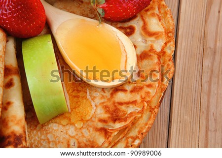 sweet food : big thin pancake with honey strawberries and apple on wooden table