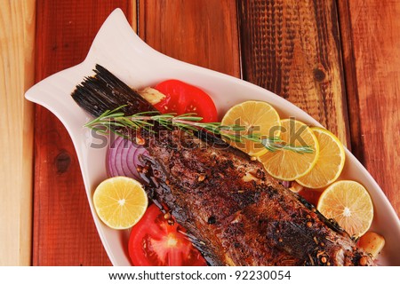 main course: whole fried sea bass served on wood with lemons,tomatoes and peppers