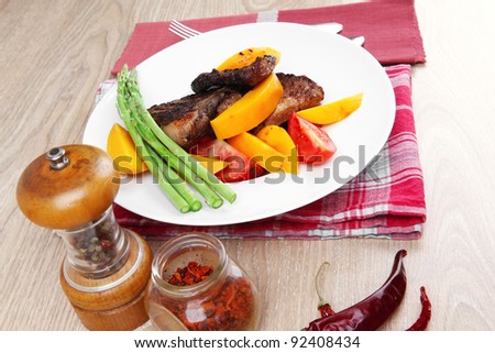meat food : grilled beef fillet with mango tomatoes and asparagus , served on white dish on red table map over wooden table