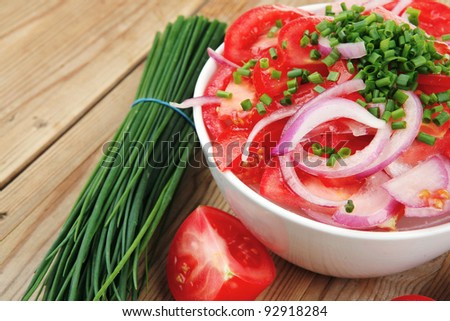 vegetable food : fresh tomato salad in white bowl with bundle of chives and raw tomatoes on twig over wooden table