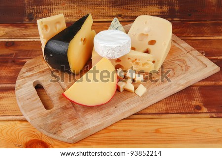many delicious aged cheeses on wooden plate